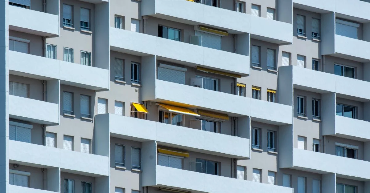 Gros plan sur la façade d'un immeuble résidentiel avec balcons et lumière du soleil projetant des ombres.