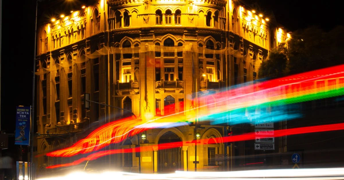 Bâtiment de la Türkiye İş Bankası illuminé la nuit avec des traînées lumineuses colorées au premier plan.