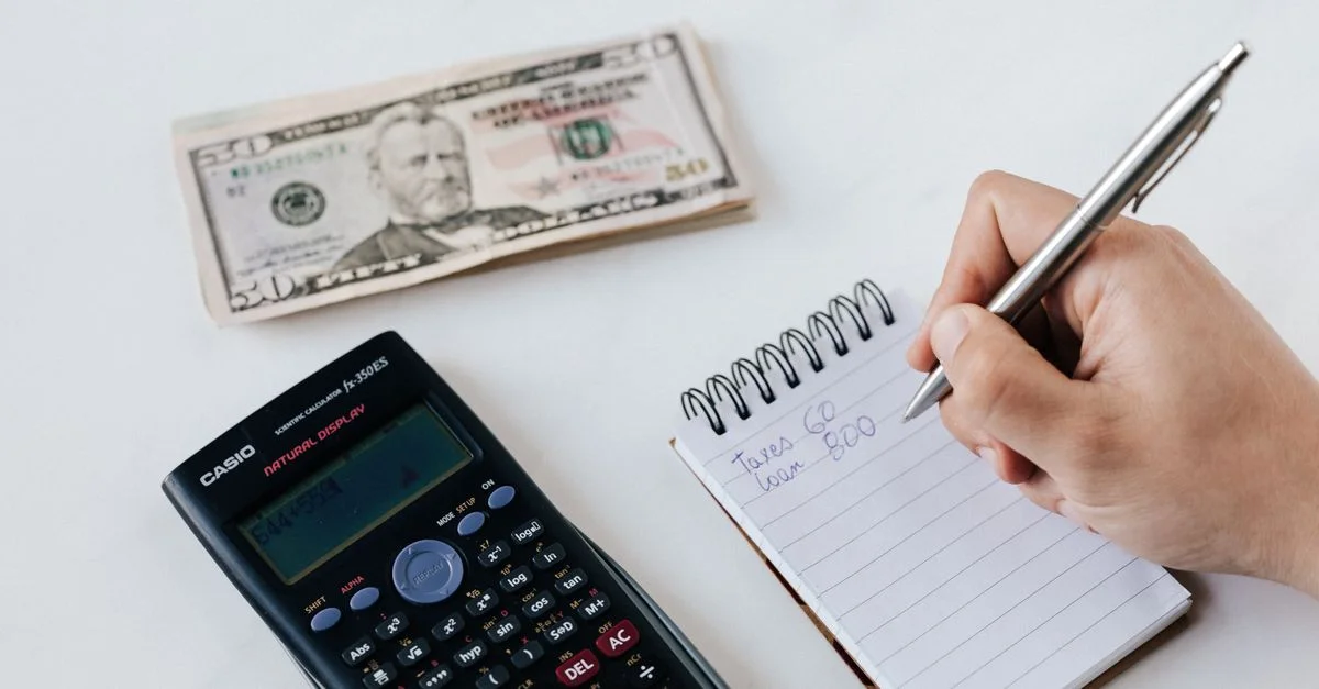 Gros plan sur des éléments de budgétisation incluant une calculatrice, de l'argent liquide et un carnet pour la planification financière.