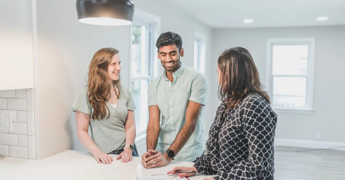 Agent immobilier consultant un couple dans une maison moderne et lumineuse. Parfait pour des thèmes de propriété et d'investissement.