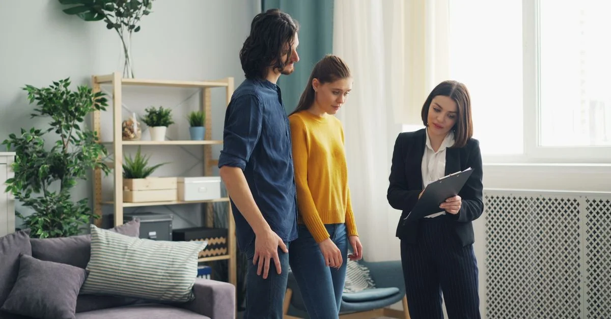 Agent immobilier consultant un couple dans un cadre moderne de salon, entouré de plantes d'intérieur.