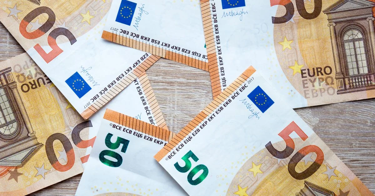 Vue de dessus de billets de 50 euros éparpillés sur une surface en bois, mettant en valeur les détails de la monnaie.