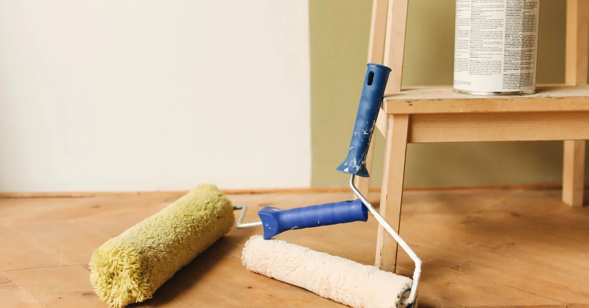 Rouleaux de peinture sur la surface du sol en bois à côté d'une boîte, prêts pour la rénovation de la maison.